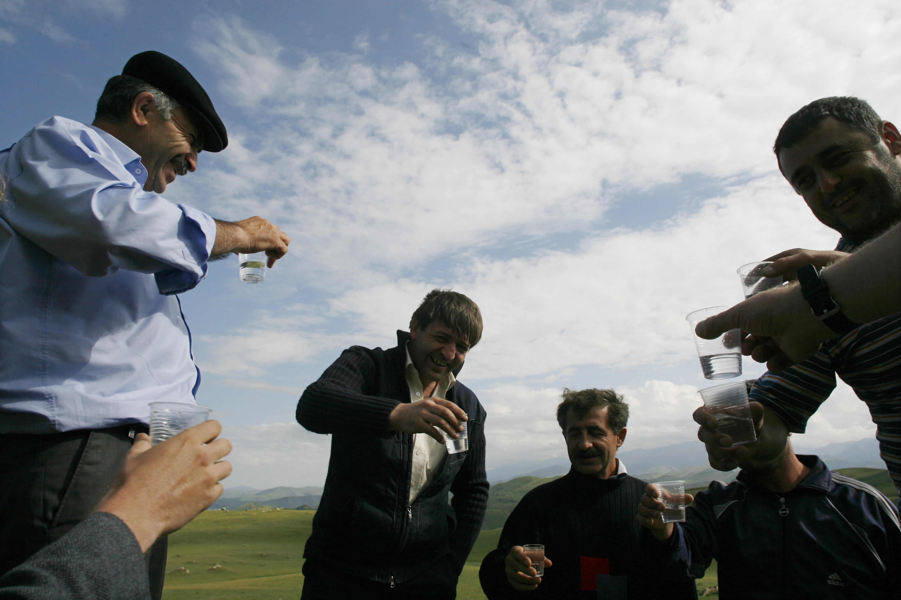 Men drink vodka near the remote mountain village of Tsovkra-1, some 3,000 metres above sea level in Russia's Caucasus region of Dagestan August 20, 2007. For children in this remote mountain village on Russia's southern fringe, after-school games means balancing on a wire suspended one storey above ground. By a quirk of history that goes so far back that in time no one really remembers, nearly every man, woman and child in Tsovkra-1 can walk the tightrope. Picture taken August 20, 2007. To match feature RUSSIA-DAGESTAN/TIGHTROPE REUTERS/Thomas Peter (RUSSIA) - RTR1T7PW