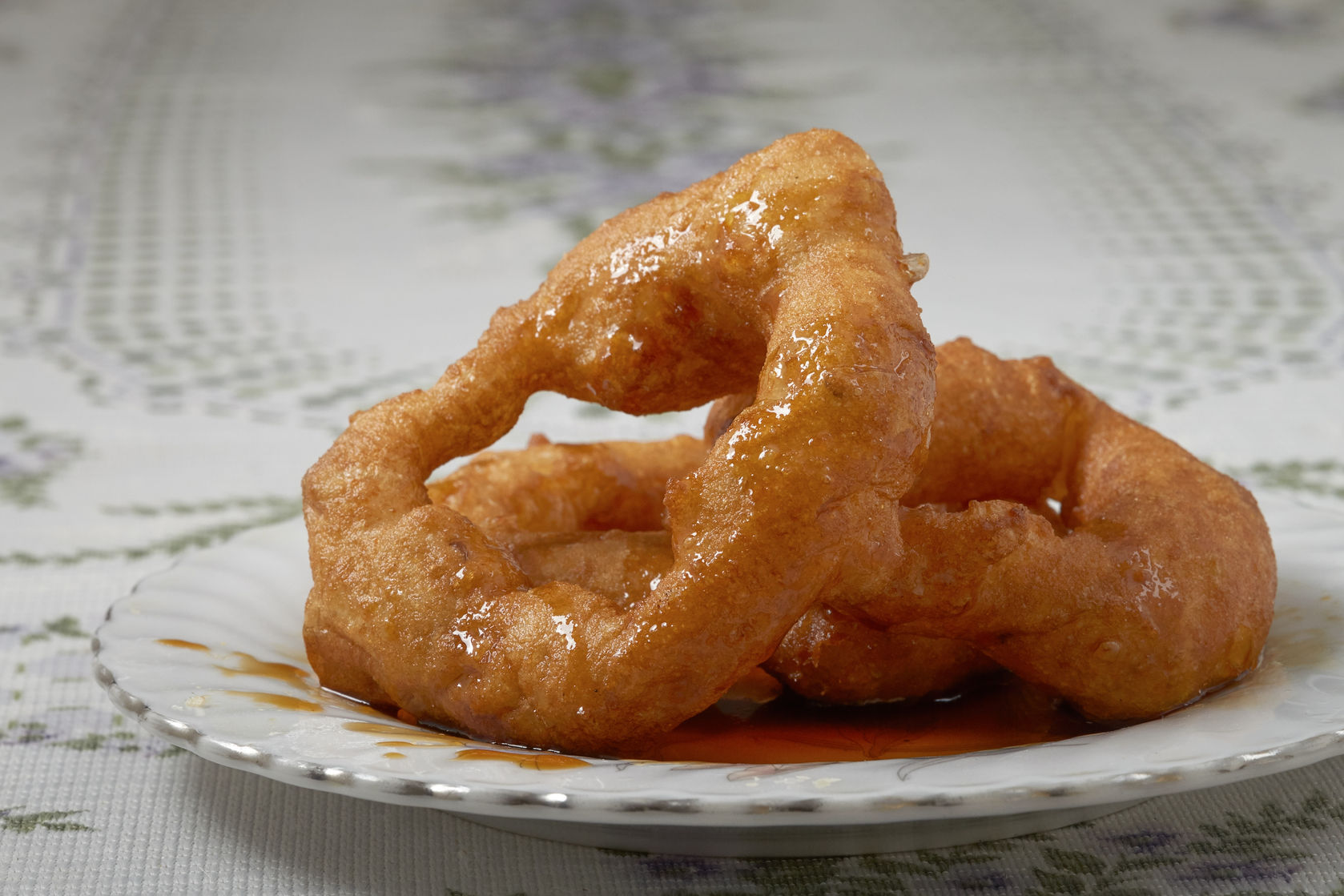 59141353 - traditional peruvian dessert picarones. made of sweet potato, pumpkin and wheat flour. fried an served whit honey figs.
