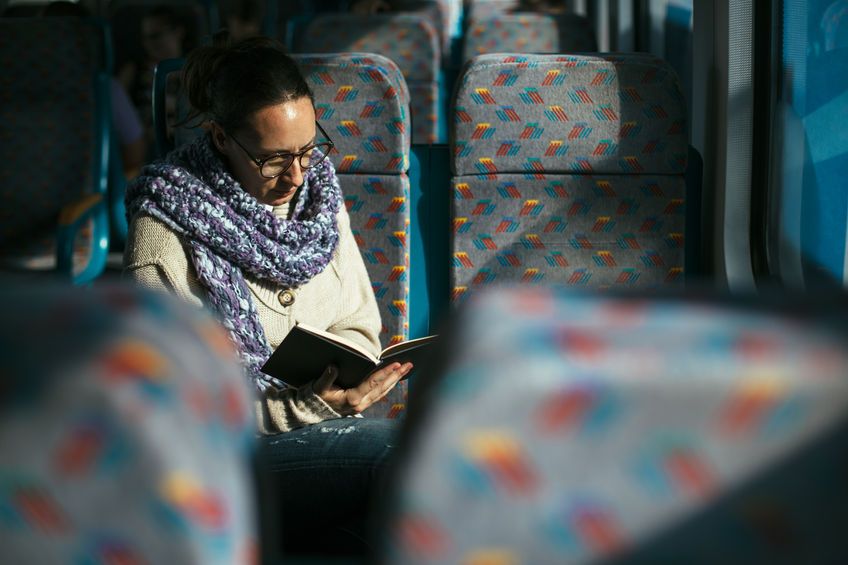 33657669 - woman reading book on train bus